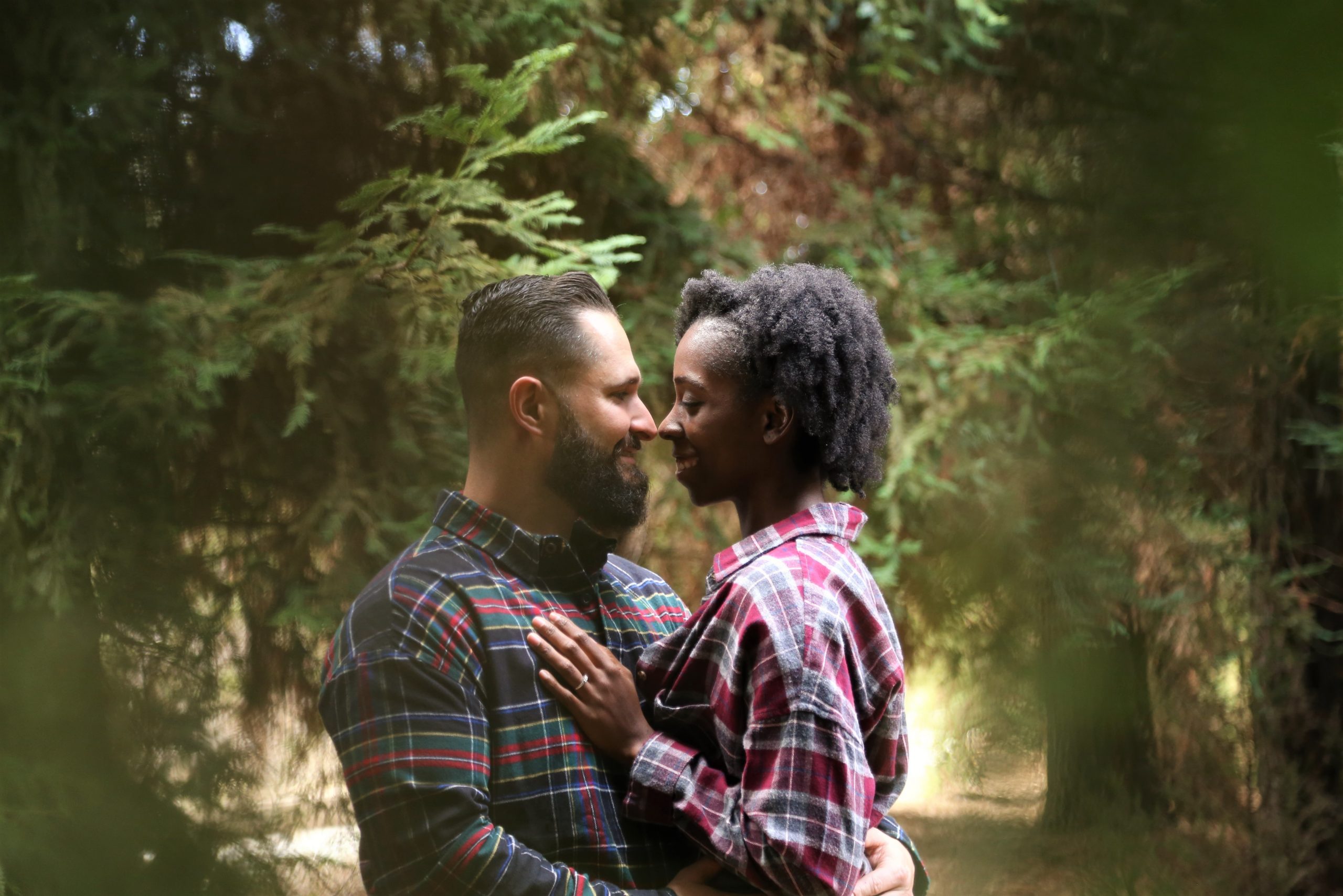 Couple holding each other in the woods.