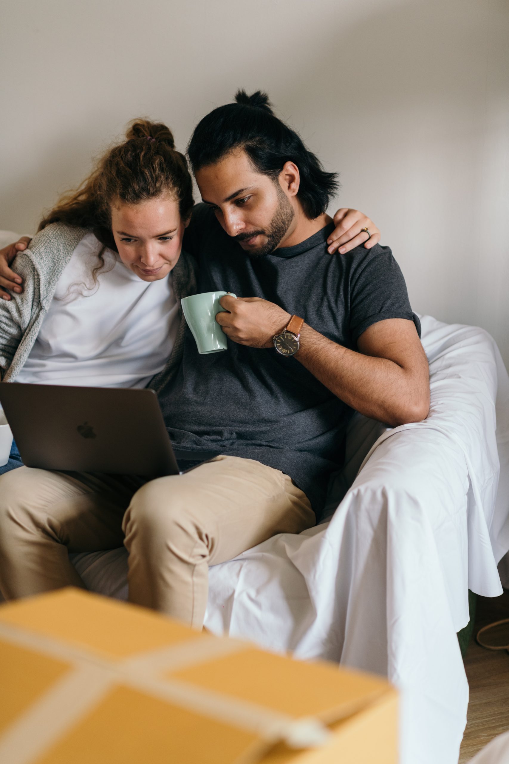 Couple sitting on couch looking at laptop screen.
