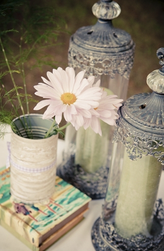 Sunflower in tin cup next to containers on table.