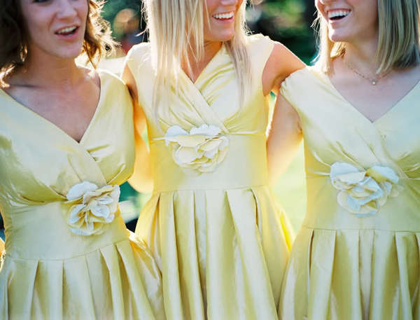 Three bridesmaids wearing the same yellow dress.