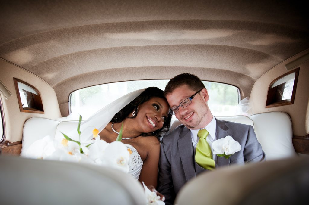 Bride and groom in back of car.