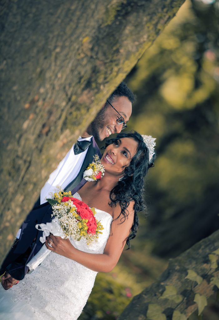 Bride and groom holding hands next to a tree outside. 