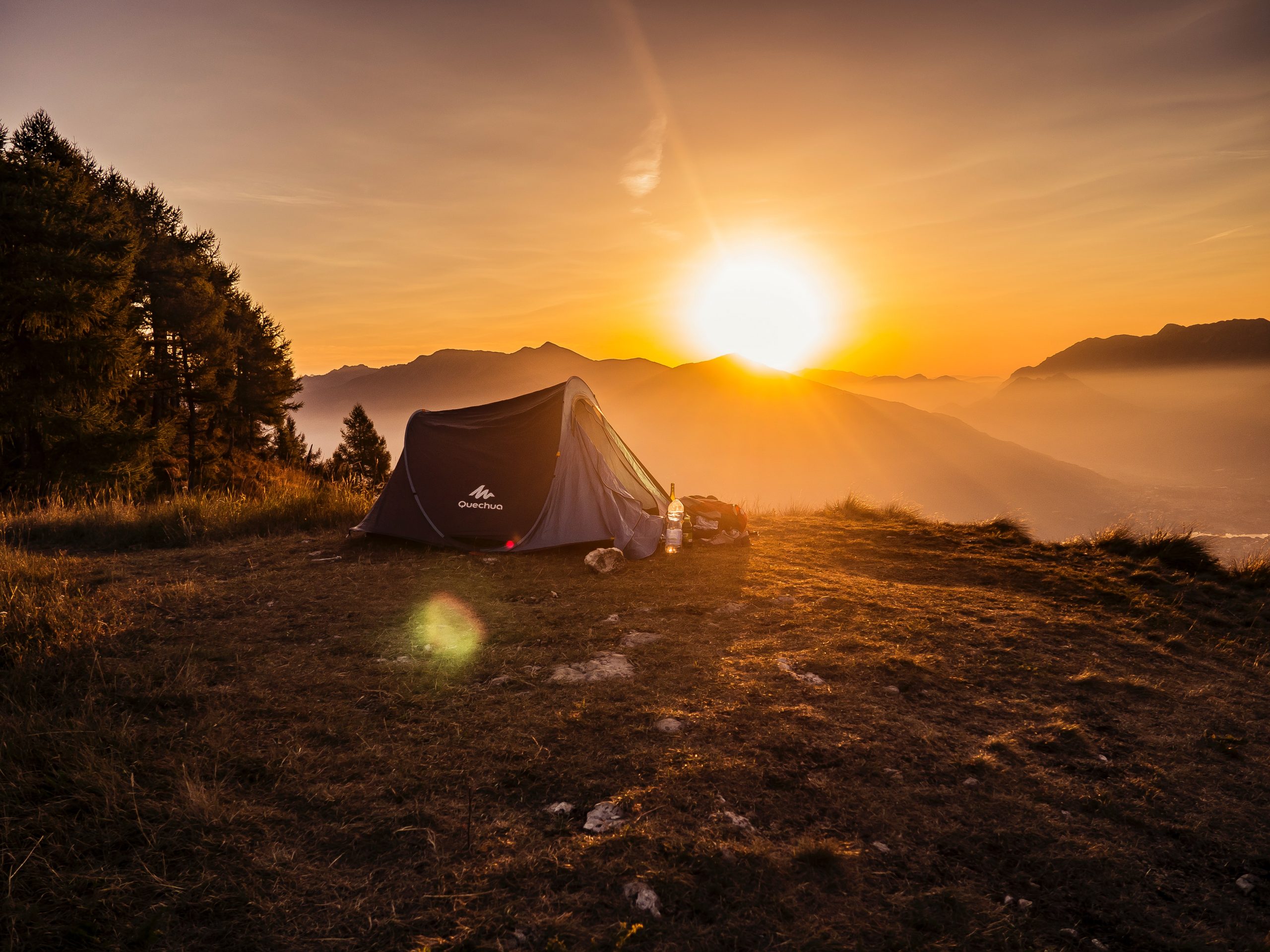 tent pitched on mountaintop campsite at sunset
