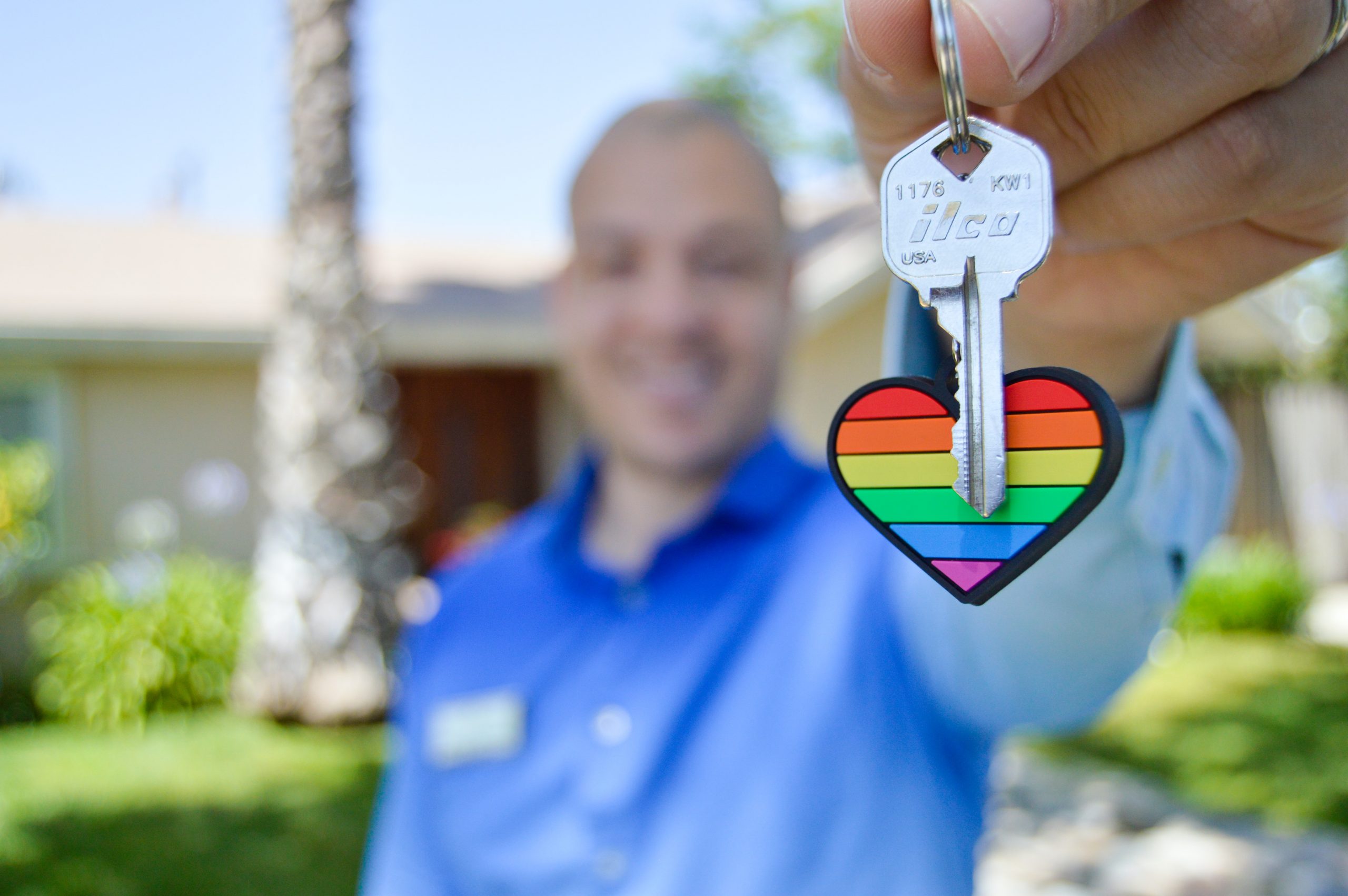 man holding up keys with rainbow keychain heart attached