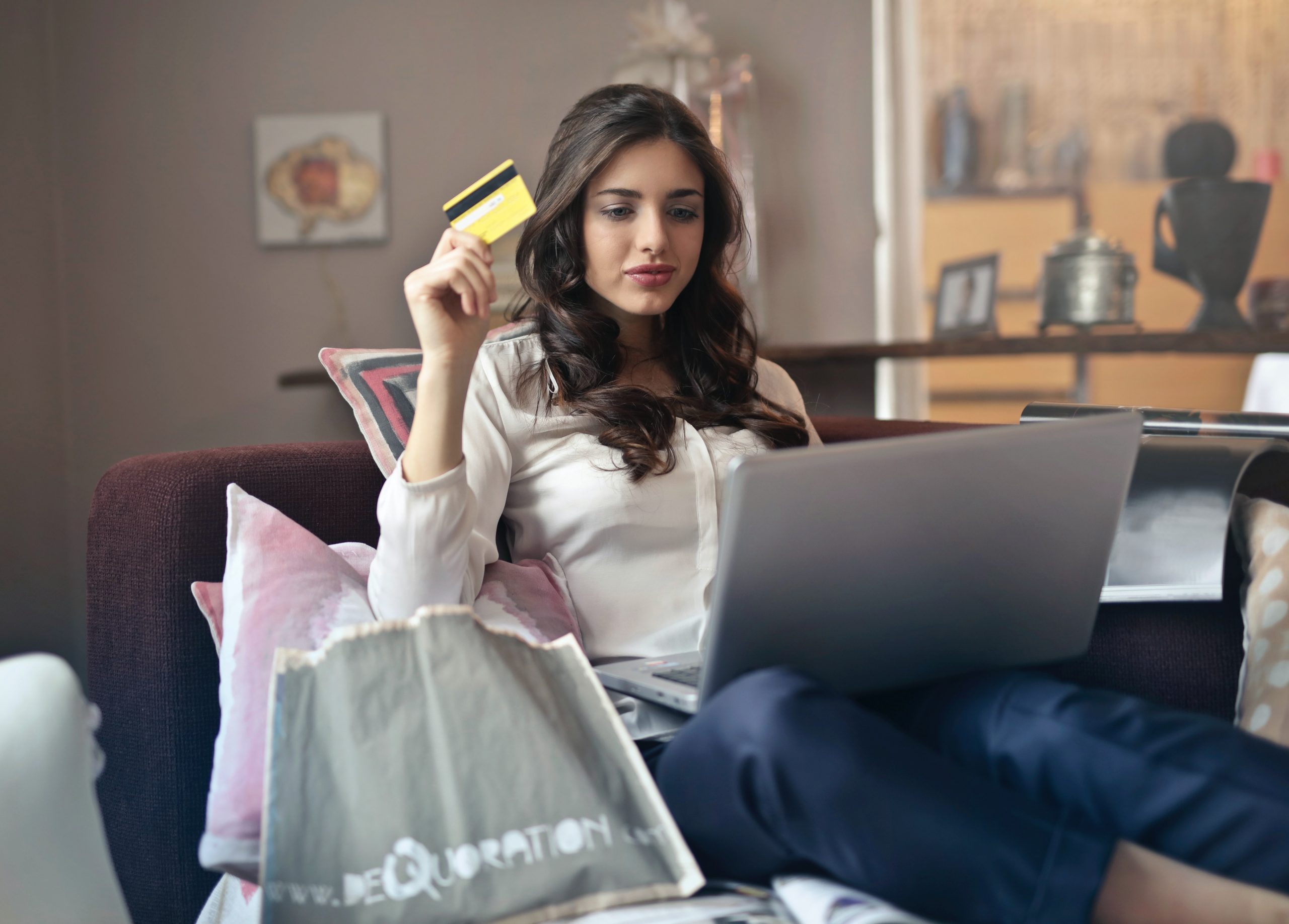 woman shopping on computer holding up gift card