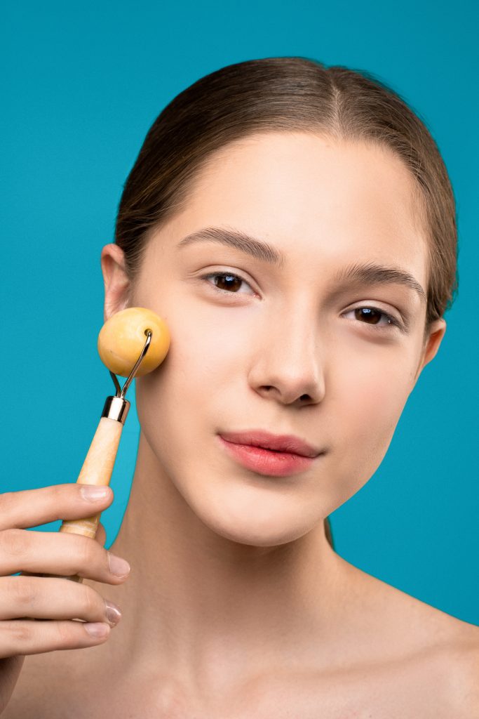 Woman using a face roller. -- DIY facial