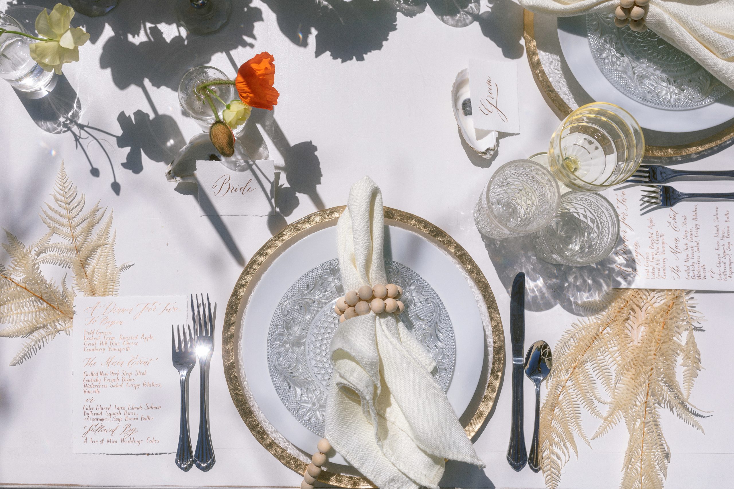 An ornate white table setting with florals and beads around a napkin