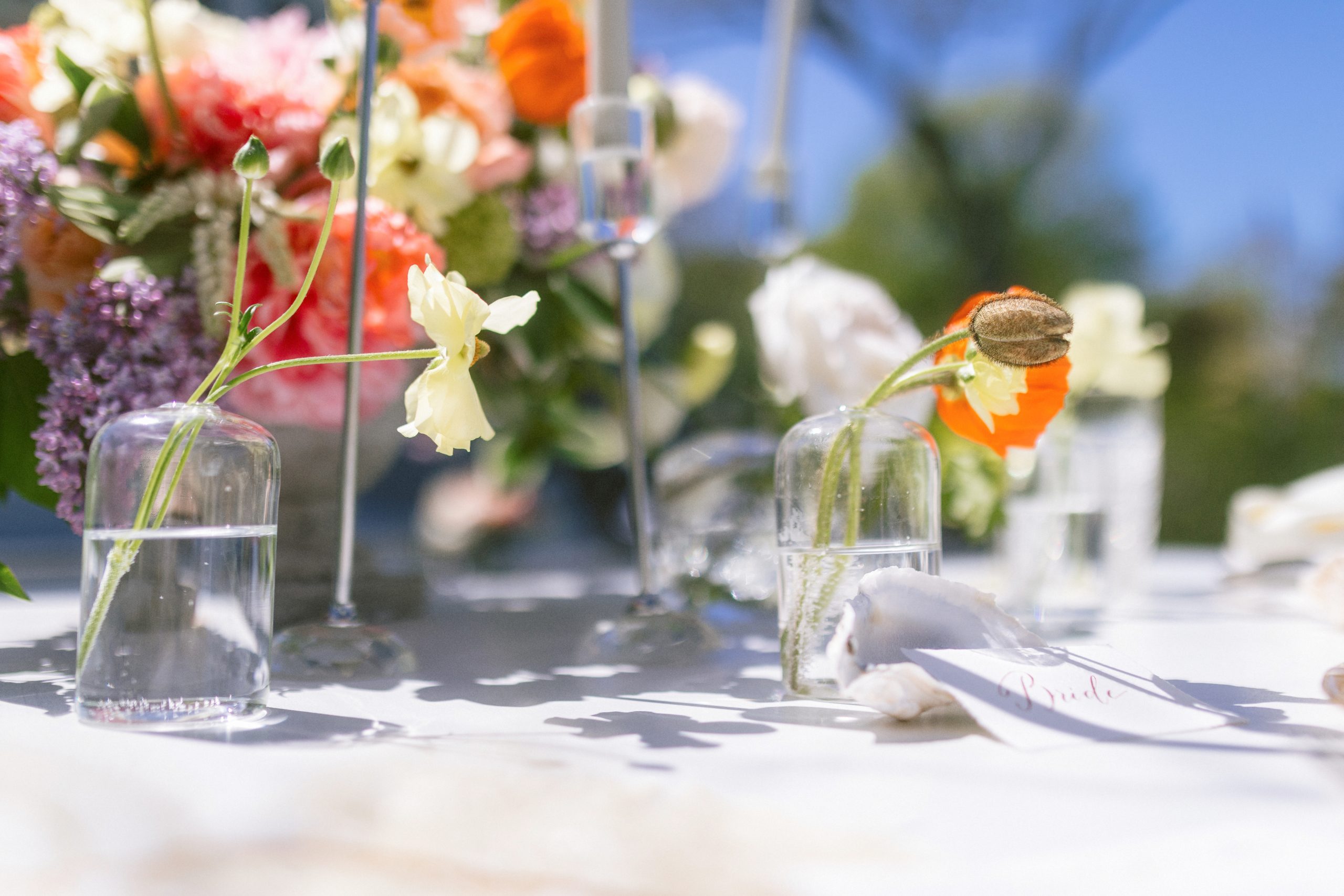 A simple orange flower in a clear glass on an ornate table setting