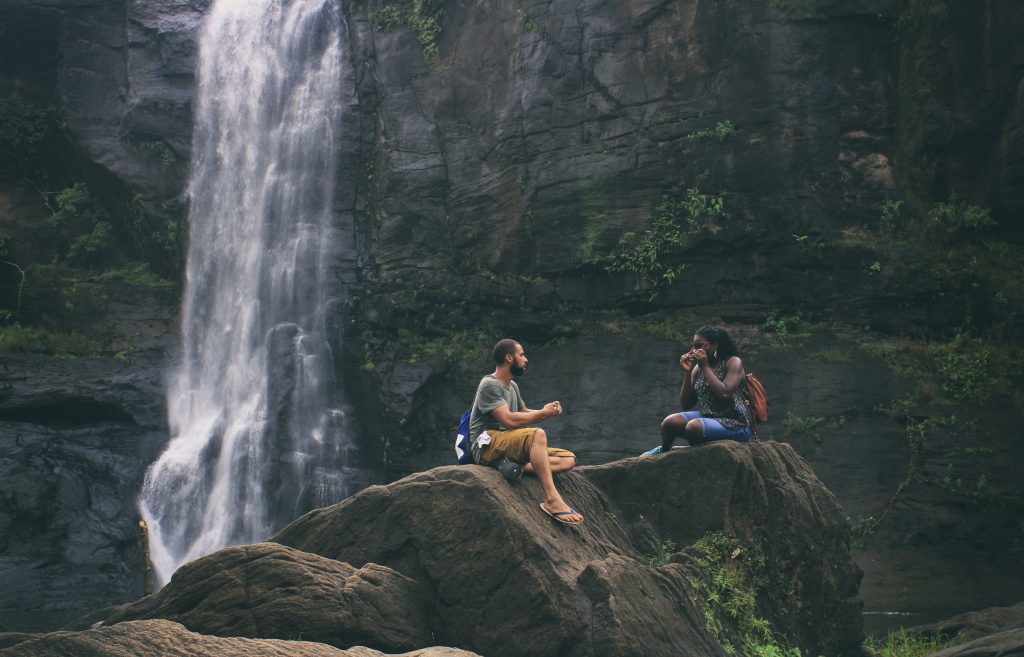 A couple sitting on a rock overlooking a waterfall