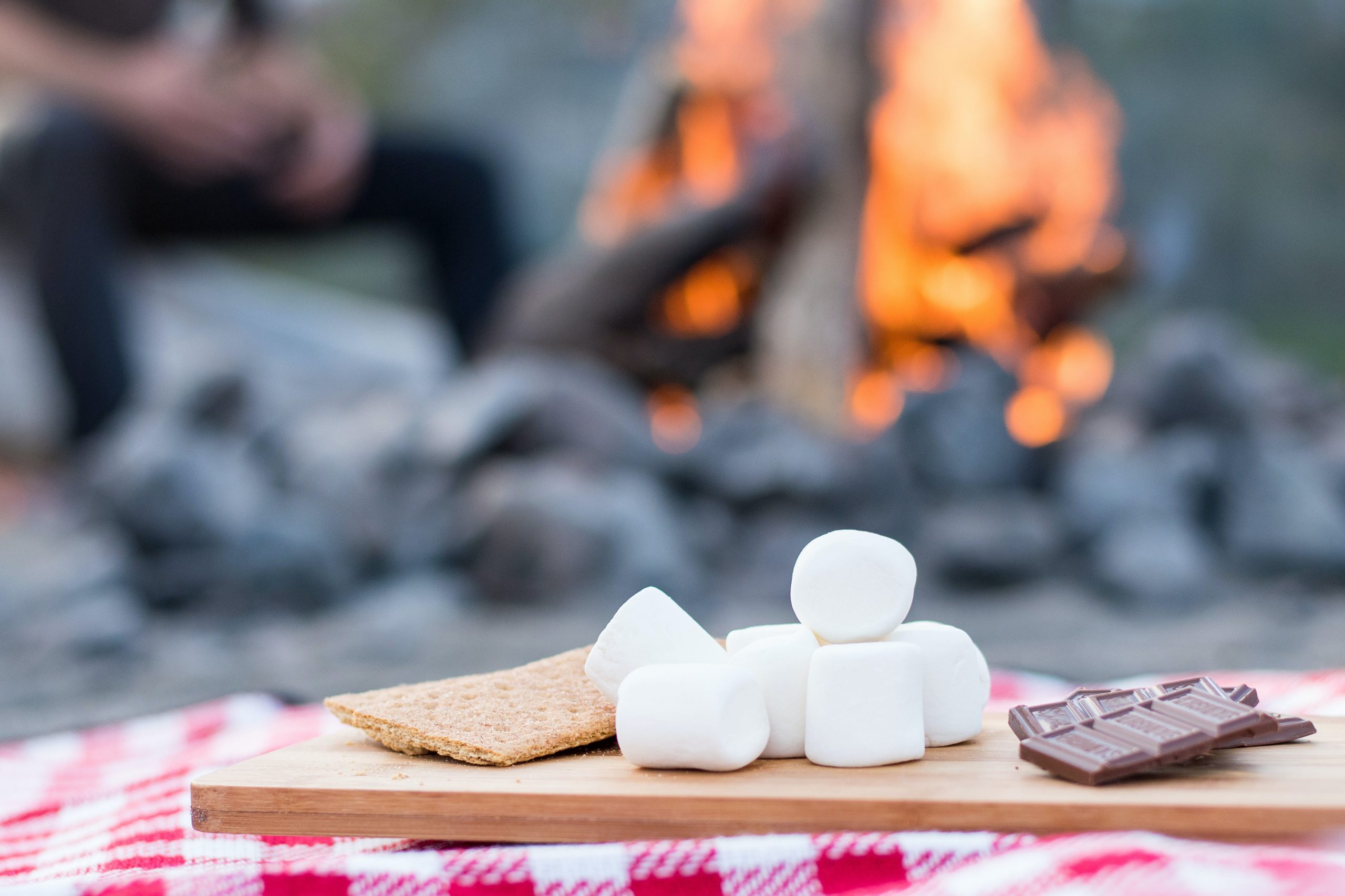 Smores ingrediants on a cutting baord by a fire pit