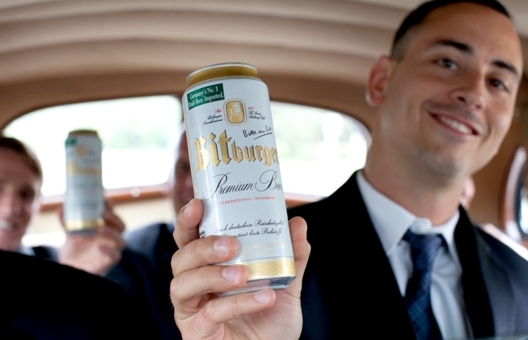 A groom holding a can of beer up for display