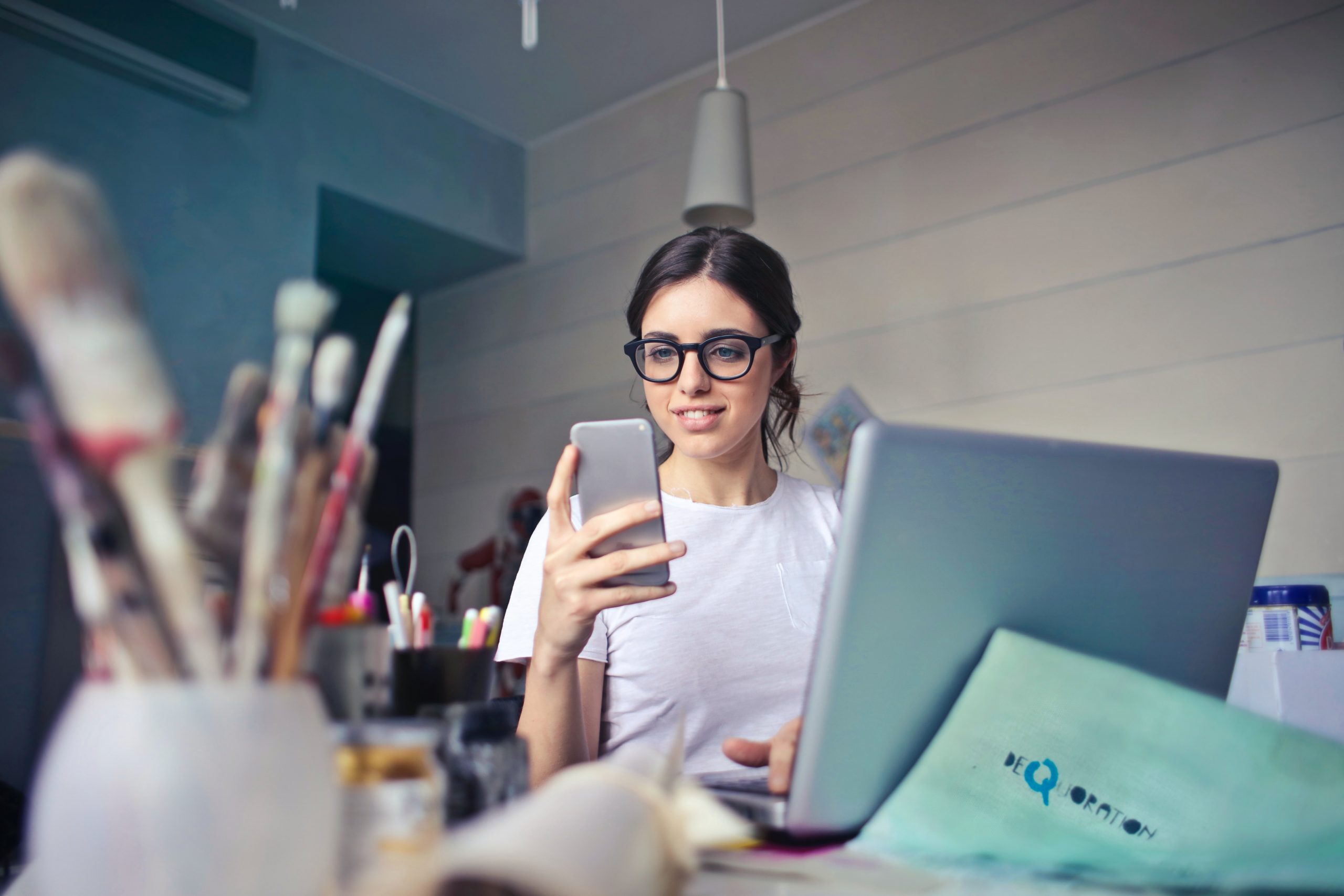 woman looking at phone while working at desk