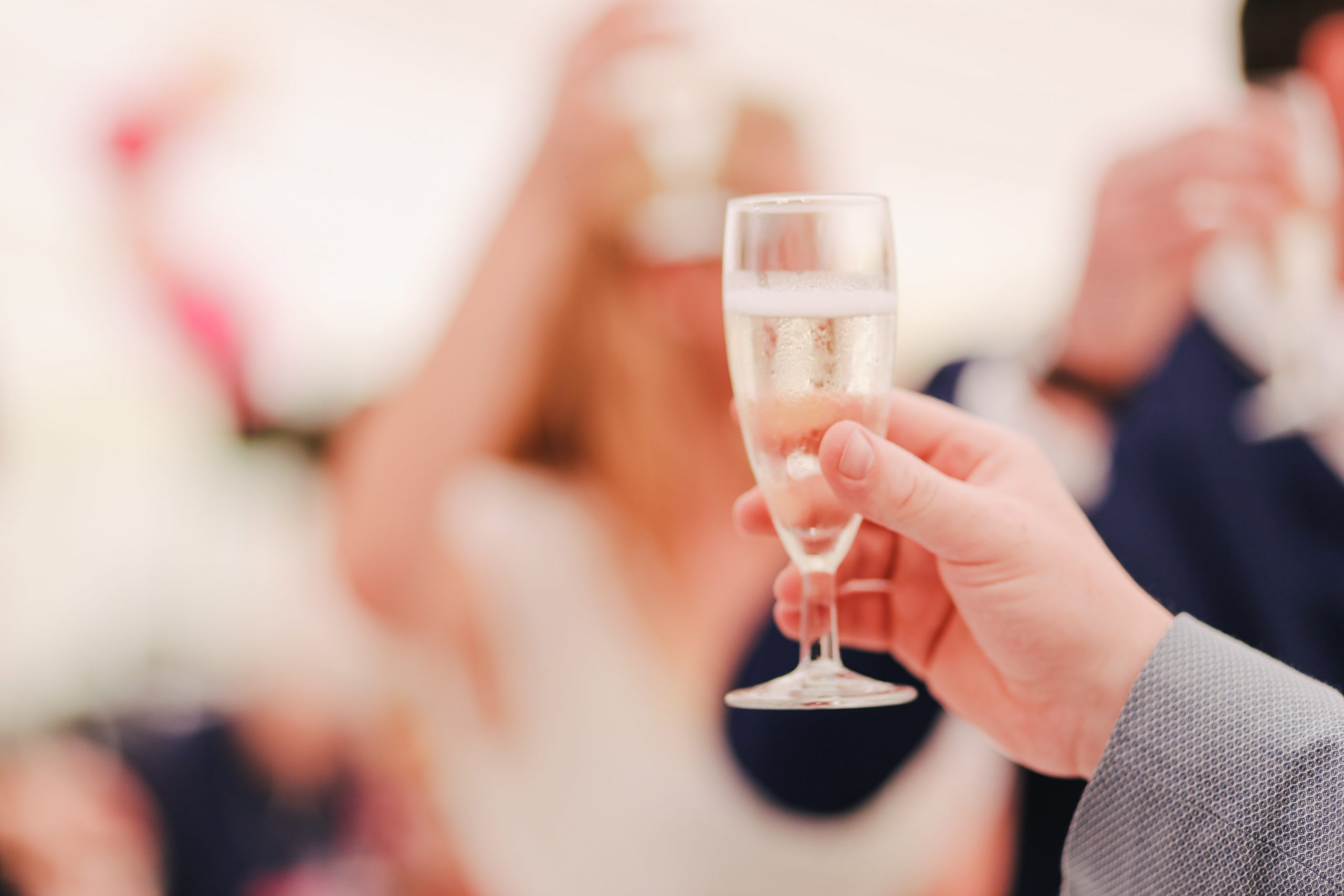 A person holding up a champagne flute giving a toast