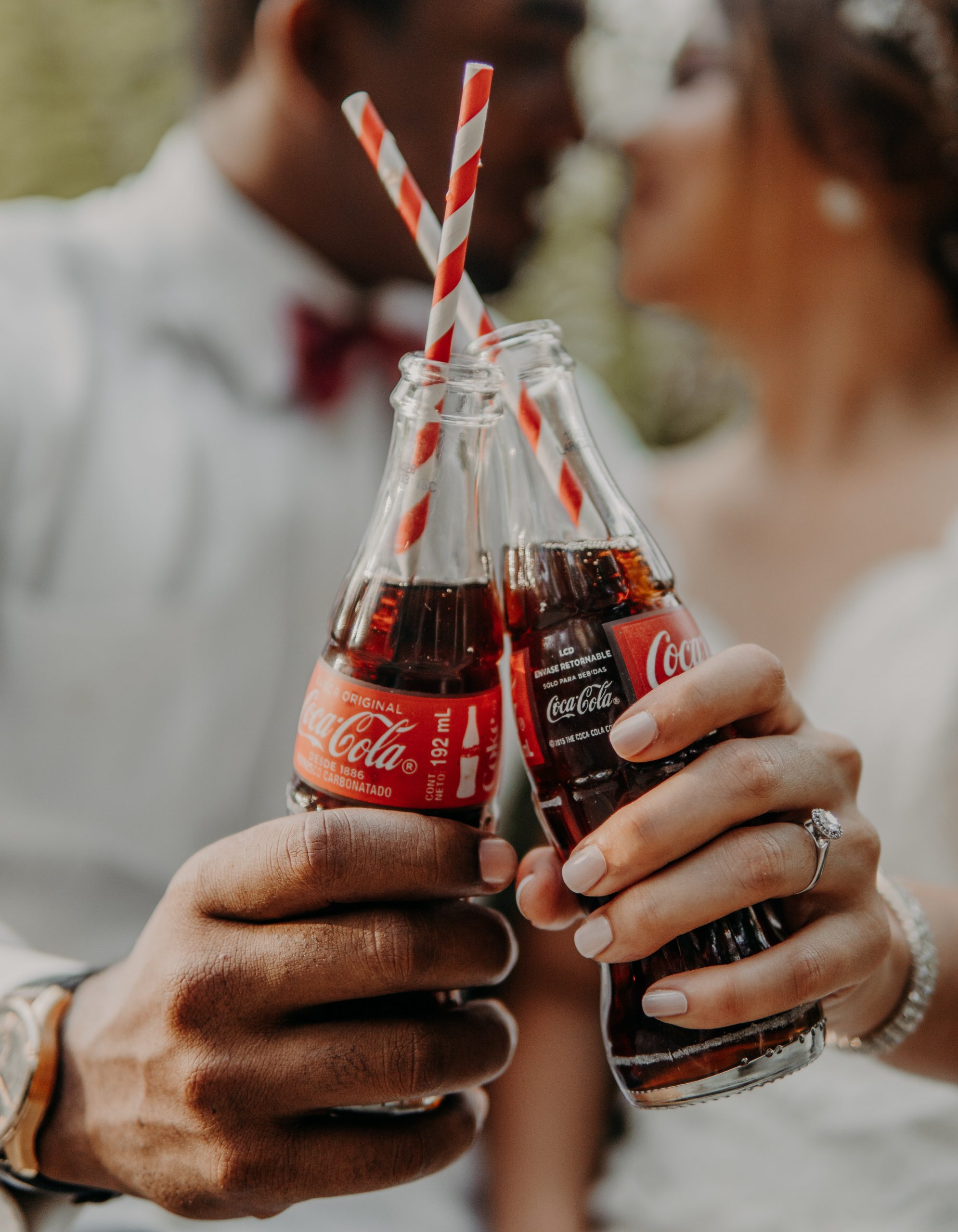 a couple cheersing cokes wearing an engagement ring